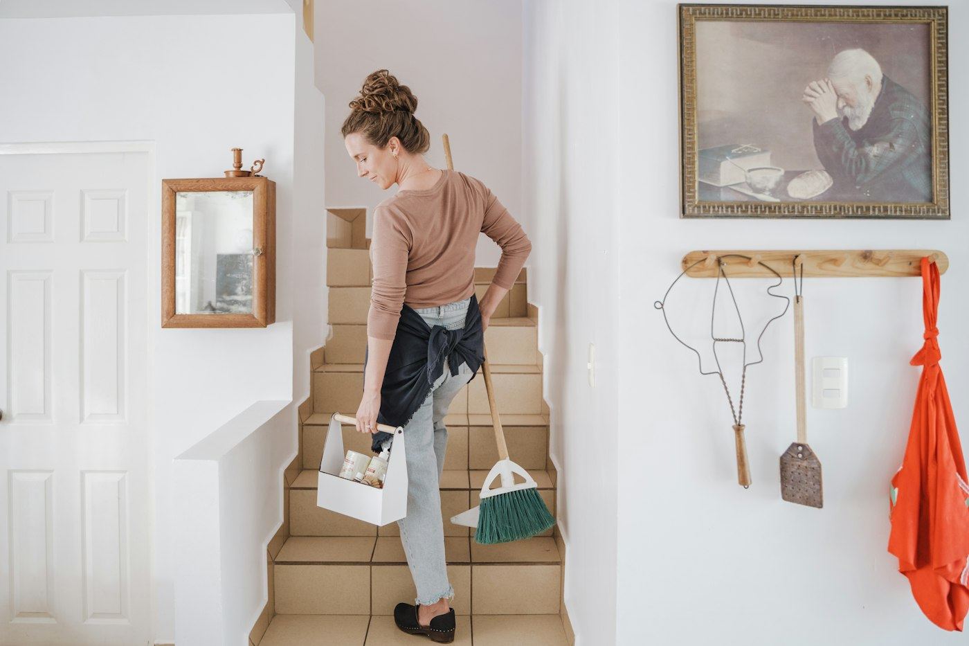 Cleaner carrying a supply caddy upstairs
