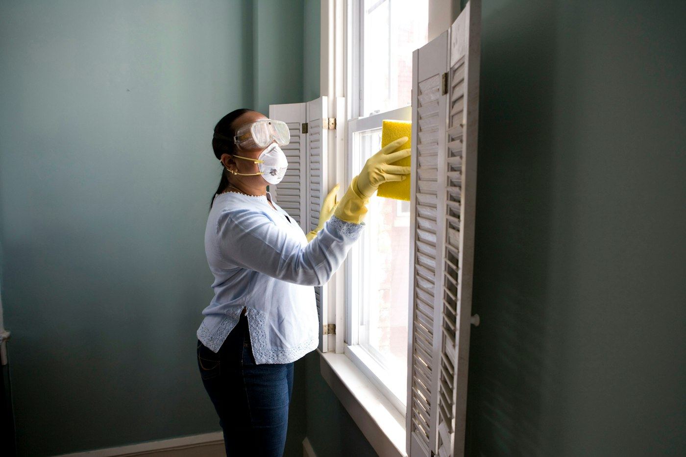 Cleaner wiping down window shutters
